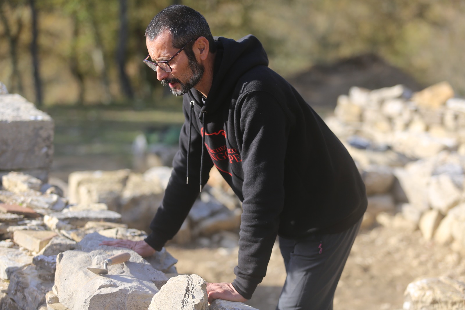 Un partecipante al lavoro presso una struttura muraria del sito.