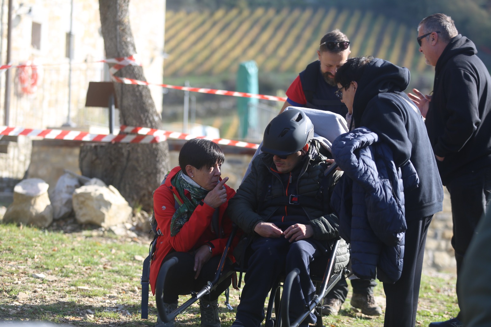 Una persona in carrozzina visita l’area di scavo insieme agli accompagnatori.